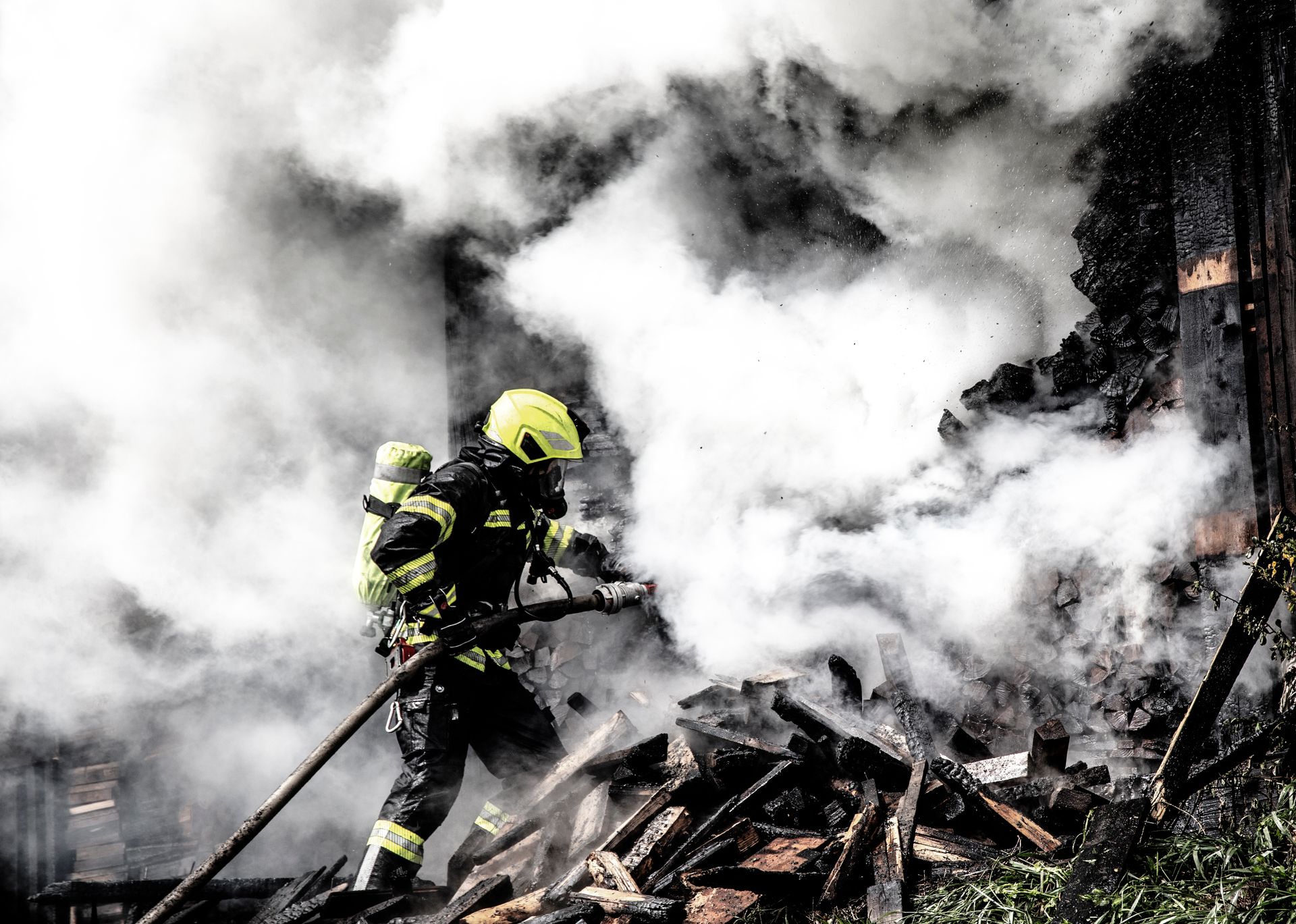 Firefighter working a structure fire amid heavy smoke